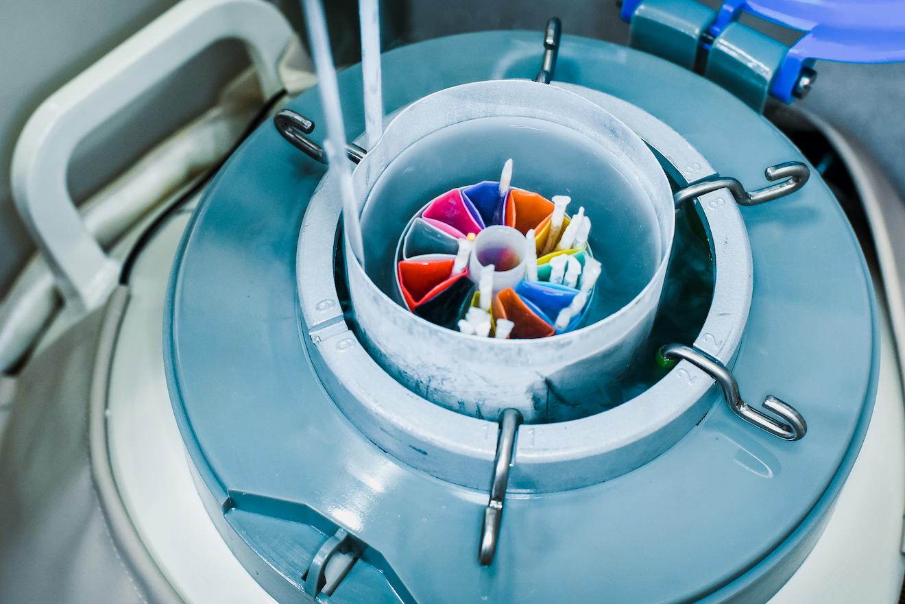 A cryogenic storage tank with a colorful canister of samples immersed in liquid nitrogen for preservation.